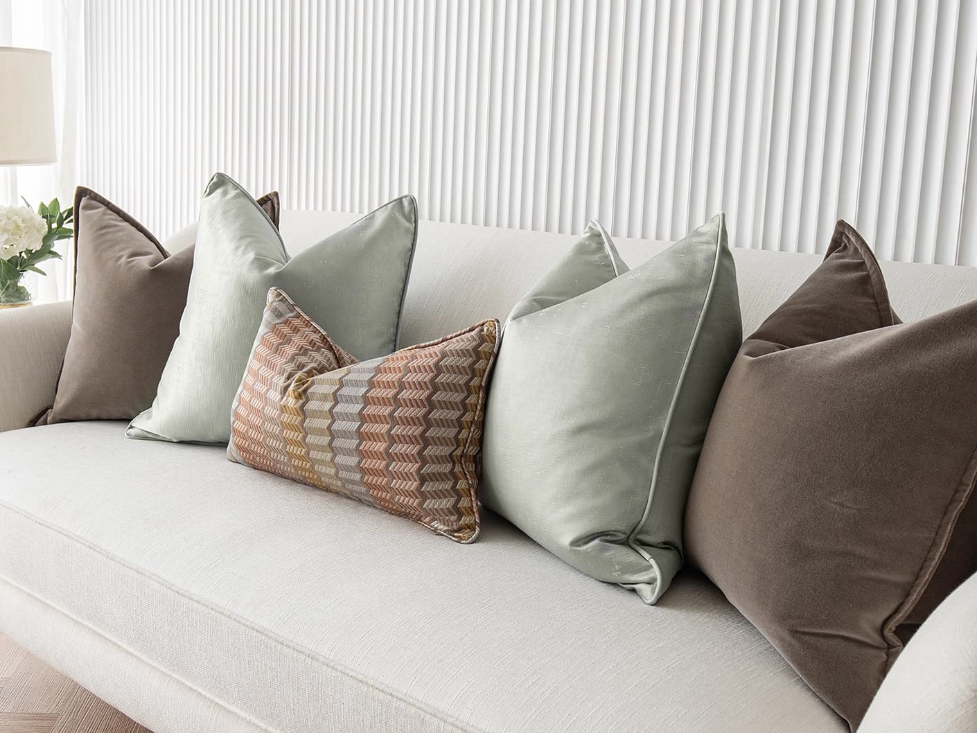 Eliazar Bundle bundle cushions in brown, orange, silver and green, shown in a lifestyle front view